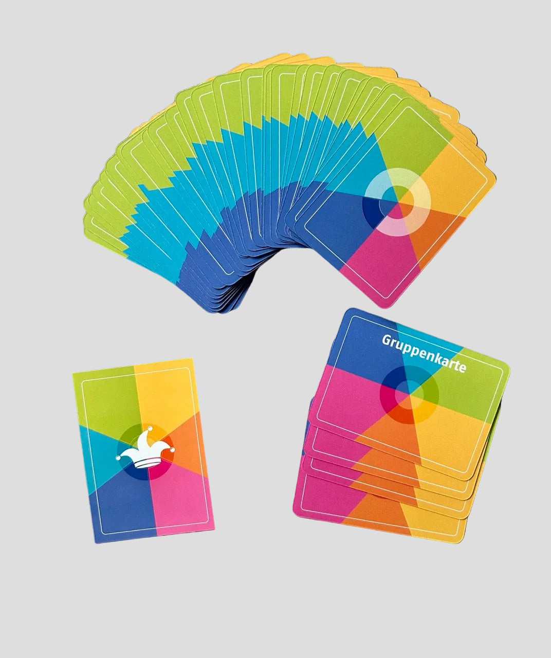 Bunte Spielkarten des Wertekreis-Spiels liegen fächerförmig auf grauem Boden. Sichtbar sind „Gruppenkarte“ und eine Karte mit Narrenkappe für eigene Werte.