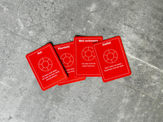 Vier orangefarbene Spielkarten liegen leicht überlappend übereinander