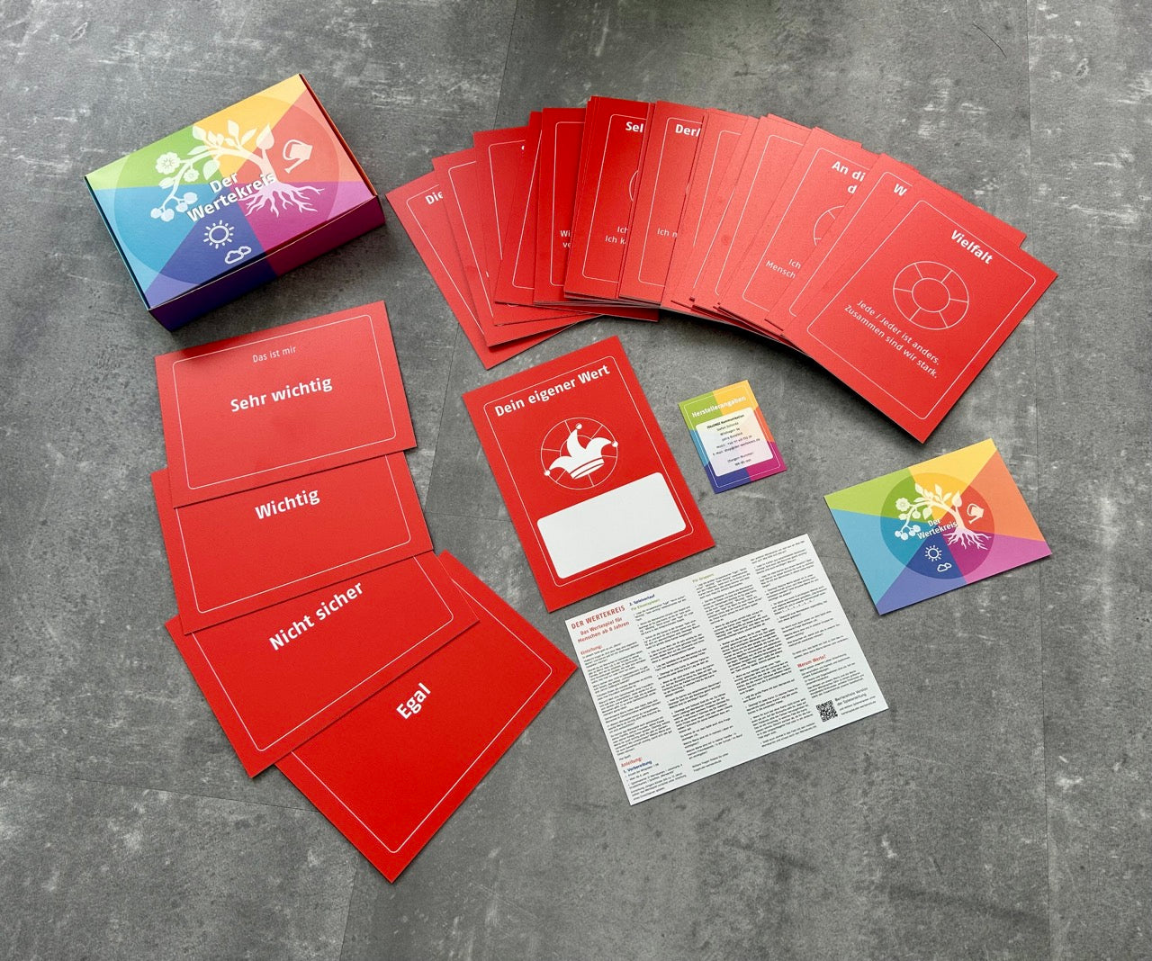 Das Wertekreis-Kartenspiel in großer Auslage im Format DIN A5: rote Wertekarten, Kategorien, bunte Box und Anleitung – lädt zum Reflektieren und Diskutieren ein.