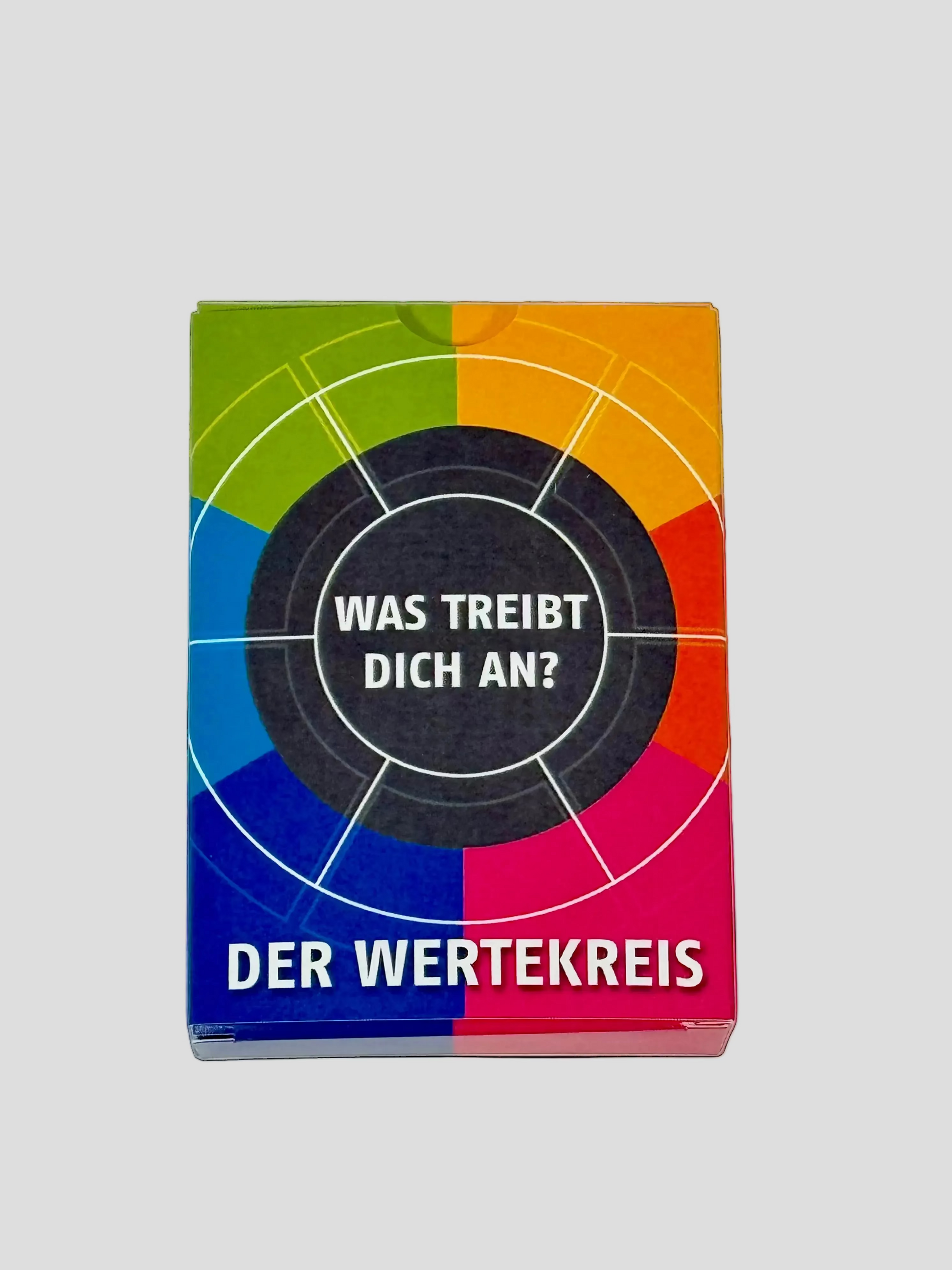 Bunte Kartenbox „Der Wertekreis“ mit Kreisgrafik und der Frage „Was treibt dich an?“ auf grauem Boden – lädt zur Reflexion persönlicher Werte ein.