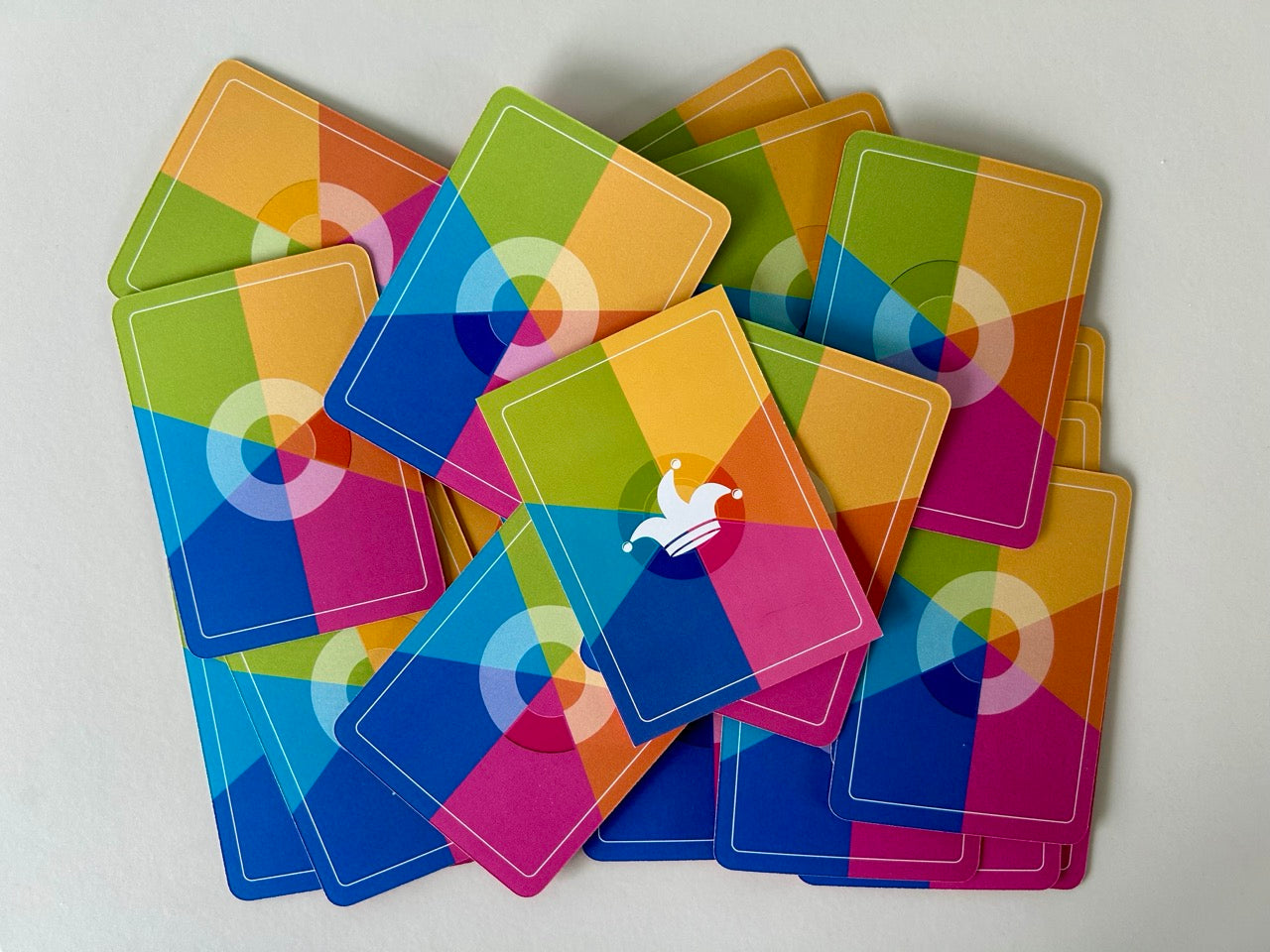 Viele bunte Spielkarten liegen übereinander. Oben auf liegt eine Karte mit einer Jokerkappe.